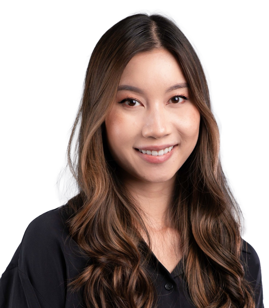 Smiling woman with long wavy brown hair in a black top, posed against a gray studio backdrop.